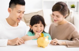 parent and daughter putting coins into piggy bank
